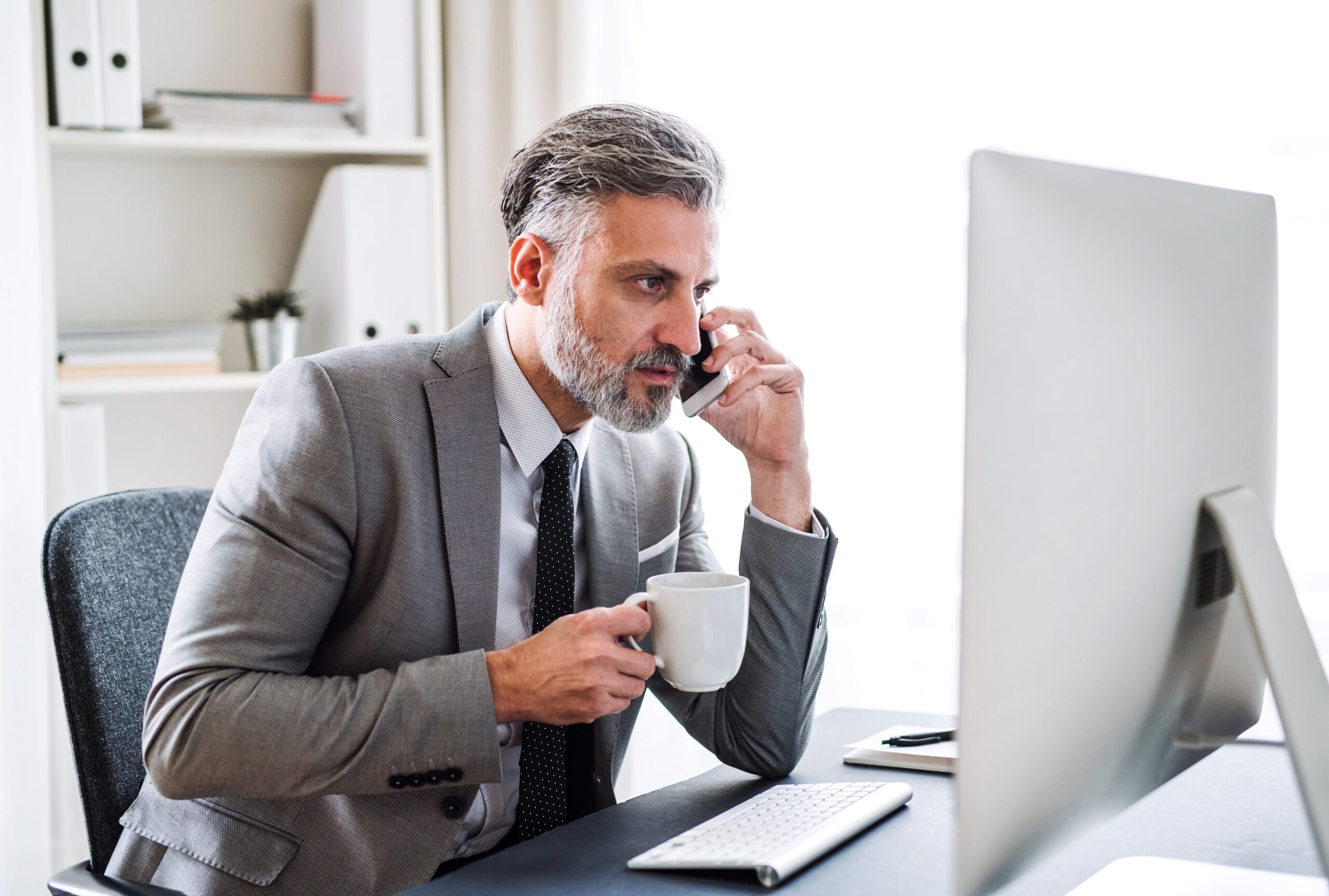 businessman with smartphone, coffee and computer sitting at the table, making a phone call.