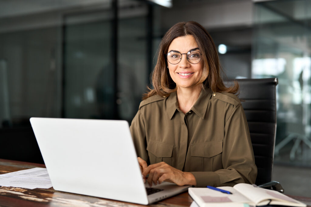 happy mature professional business woman with laptop in office, portrait.