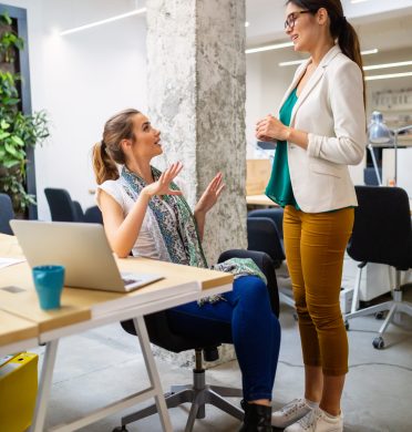 attractive businesswoman having fun conversation with colleague during break in office