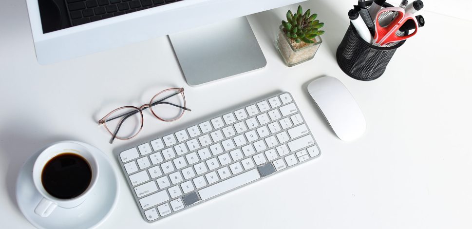 high angle view of workspace with computer, keyboard, mouse, coffee, and glasses at office desk