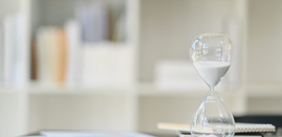 hourglass on wooden office table with financial documents. time management concept